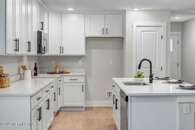 kitchen with appliances with stainless steel finishes, white cabinets, a sink, and light countertops