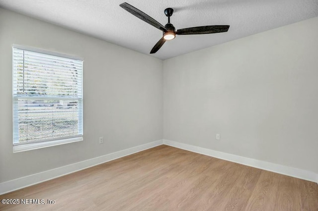 unfurnished room featuring light wood finished floors, a ceiling fan, baseboards, and a textured ceiling