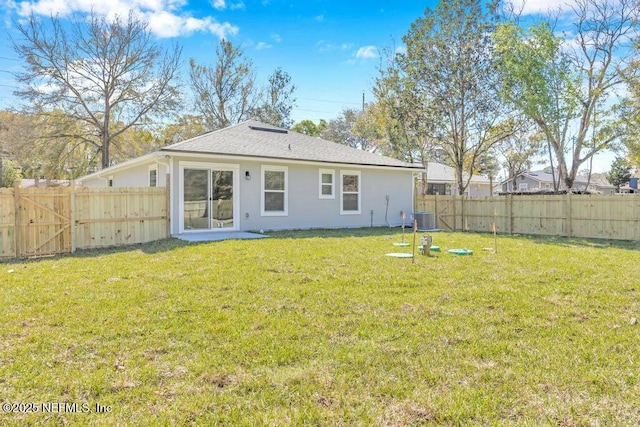 rear view of house featuring a yard, central AC, and a fenced backyard