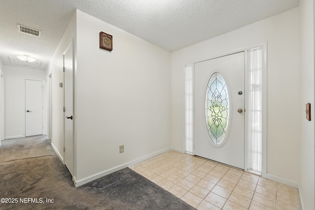 foyer featuring light tile patterned floors, visible vents, baseboards, and a textured ceiling