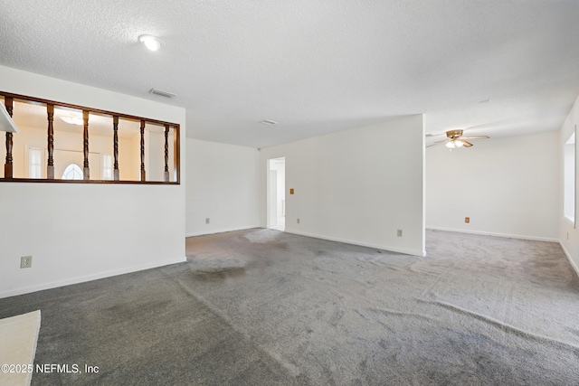 spare room featuring baseboards, a ceiling fan, visible vents, and a textured ceiling