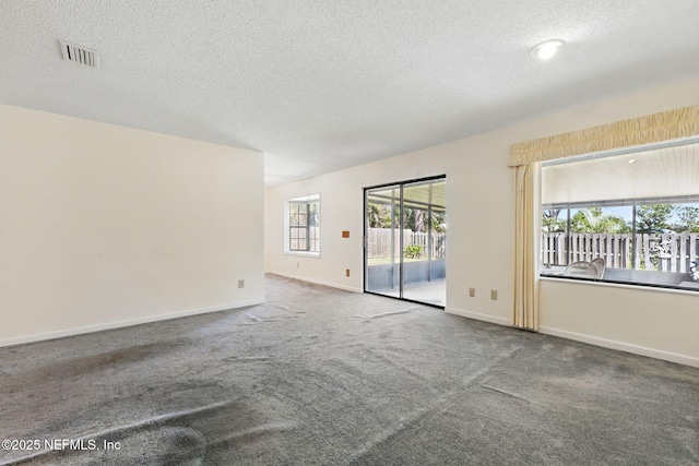 unfurnished room with visible vents, baseboards, carpet, and a textured ceiling