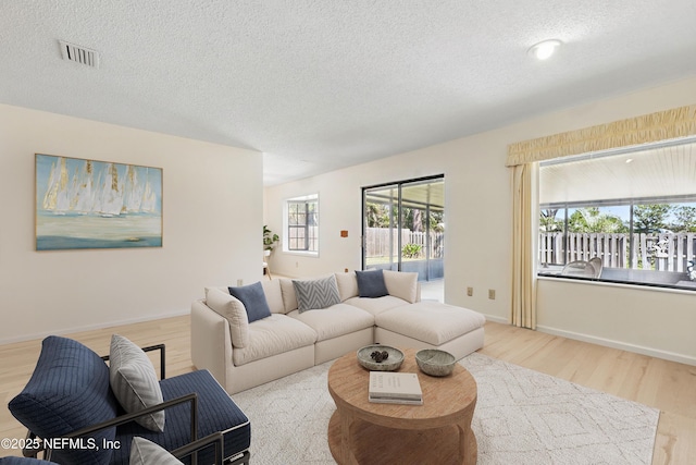 living area featuring baseboards, wood finished floors, visible vents, and a textured ceiling