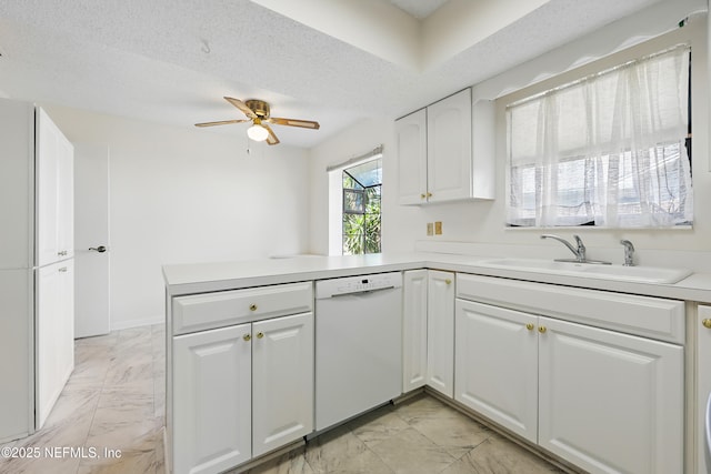 kitchen with marble finish floor, a sink, a peninsula, white cabinets, and dishwasher