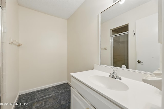 full bathroom with vanity, baseboards, a stall shower, and a textured ceiling