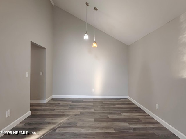 empty room featuring high vaulted ceiling, baseboards, and wood finished floors