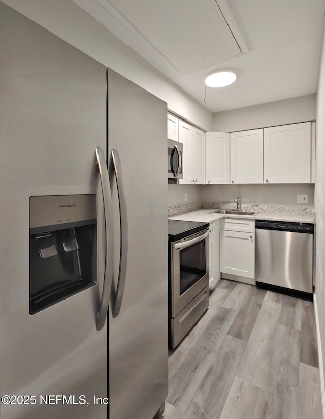 kitchen featuring white cabinets, light wood-style floors, stainless steel appliances, and a sink