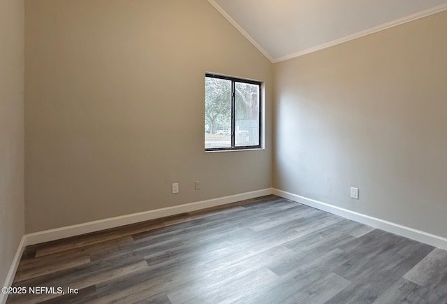 empty room with lofted ceiling, ornamental molding, dark wood-style floors, and baseboards