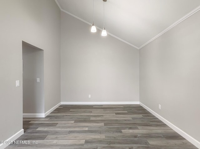 empty room with lofted ceiling, crown molding, baseboards, and wood finished floors