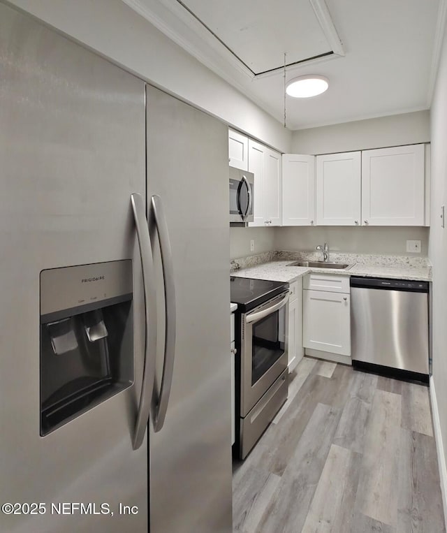 kitchen featuring stainless steel appliances, white cabinetry, a sink, and light wood-style flooring