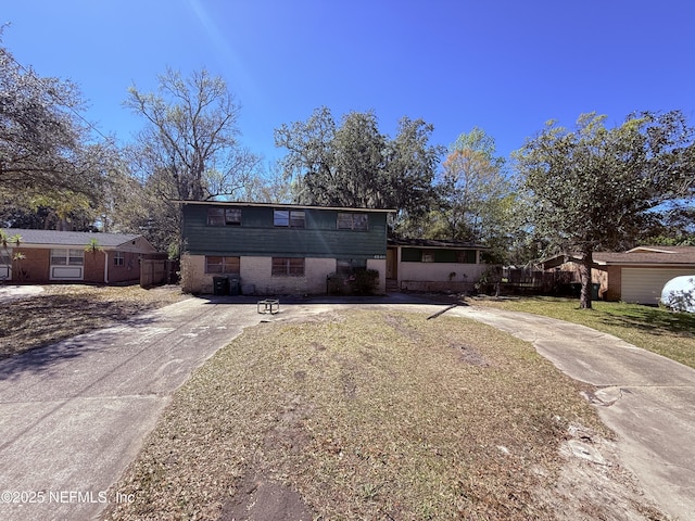 view of front of home featuring concrete driveway, brick siding, fence, and a front lawn