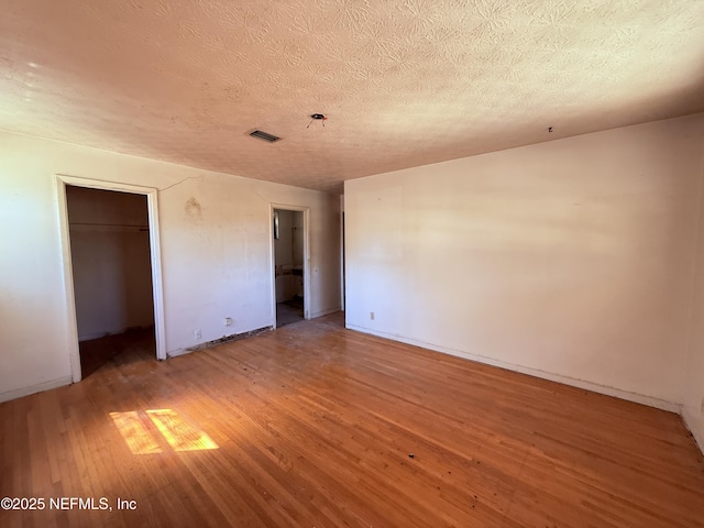 interior space with light wood-type flooring, a closet, visible vents, and a textured ceiling