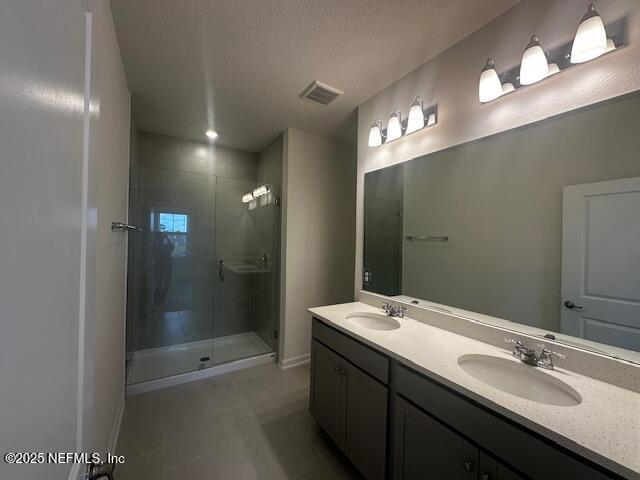 bathroom with a sink, visible vents, and a stall shower