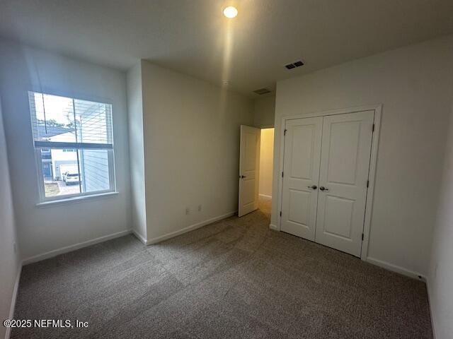 unfurnished bedroom with a closet, visible vents, baseboards, and carpet