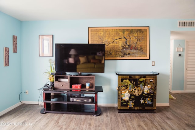 living room featuring wood finished floors, visible vents, and baseboards