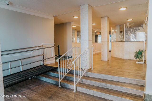 stairs featuring crown molding and wood finished floors