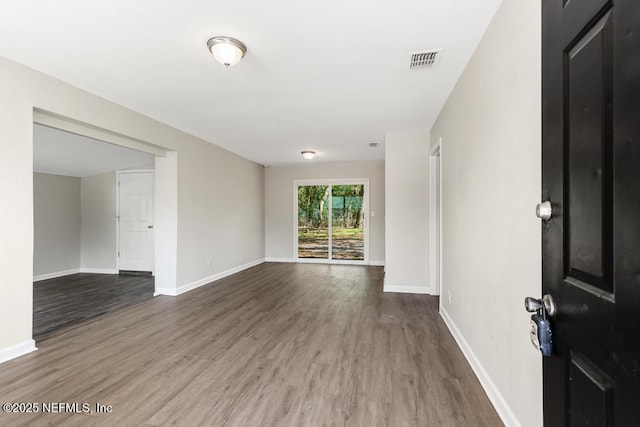 unfurnished room featuring baseboards, visible vents, and wood finished floors