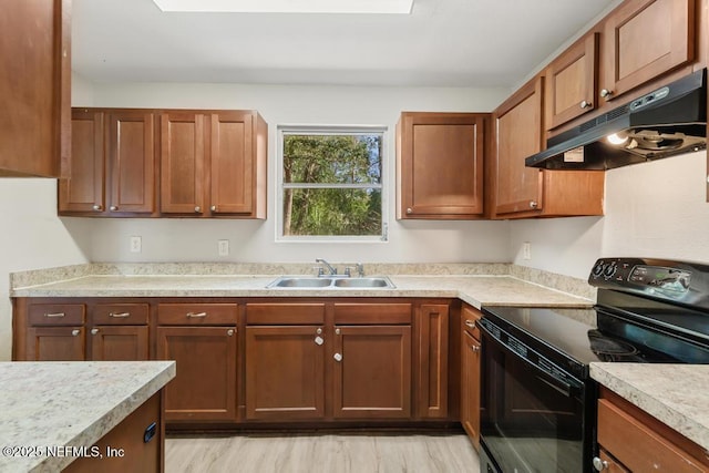 kitchen featuring black / electric stove, under cabinet range hood, a sink, light countertops, and light wood-type flooring