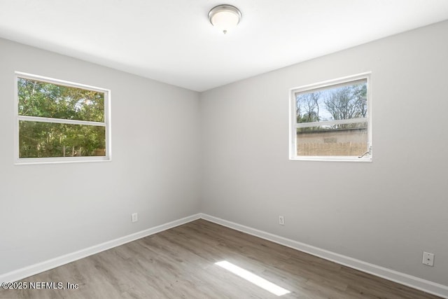 unfurnished room with a wealth of natural light, baseboards, and wood finished floors