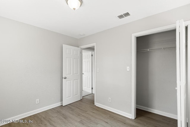 unfurnished bedroom with wood finished floors, visible vents, and baseboards