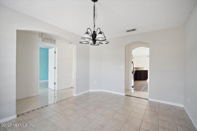 spare room featuring arched walkways, visible vents, baseboards, and light tile patterned flooring