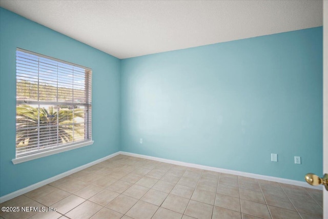 unfurnished room with light tile patterned floors and baseboards