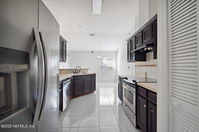 kitchen featuring light tile patterned floors, decorative backsplash, stainless steel appliances, light countertops, and under cabinet range hood