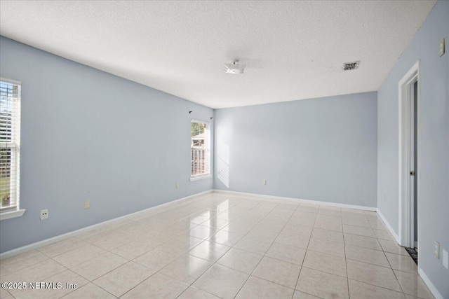 spare room with visible vents, a textured ceiling, baseboards, and light tile patterned floors