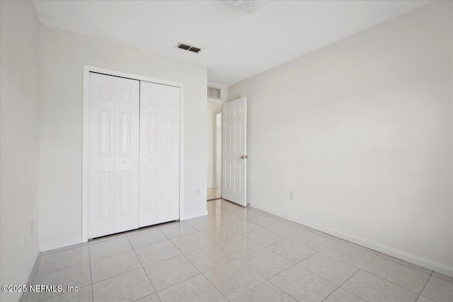 unfurnished bedroom with a closet, light tile patterned flooring, visible vents, and baseboards