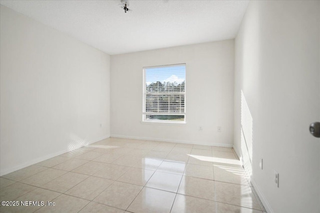 tiled spare room featuring baseboards