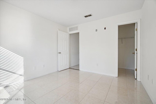 empty room featuring light tile patterned floors, baseboards, and visible vents