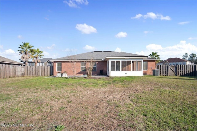 rear view of property with brick siding, a lawn, and a sunroom