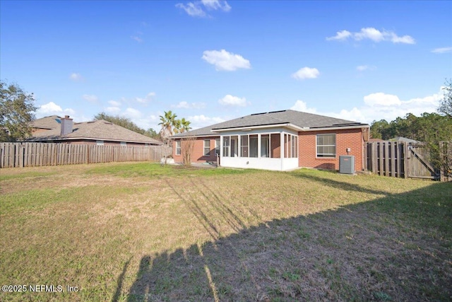 back of house featuring a yard, brick siding, central AC unit, and fence private yard