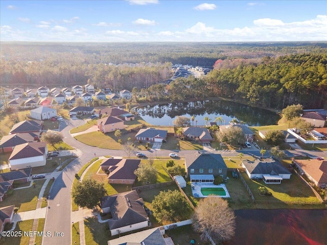 drone / aerial view featuring a water view, a wooded view, and a residential view