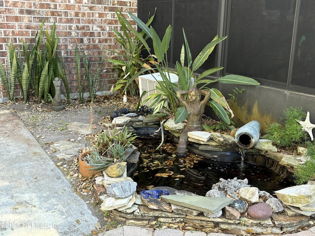 exterior details with brick siding and a garden pond