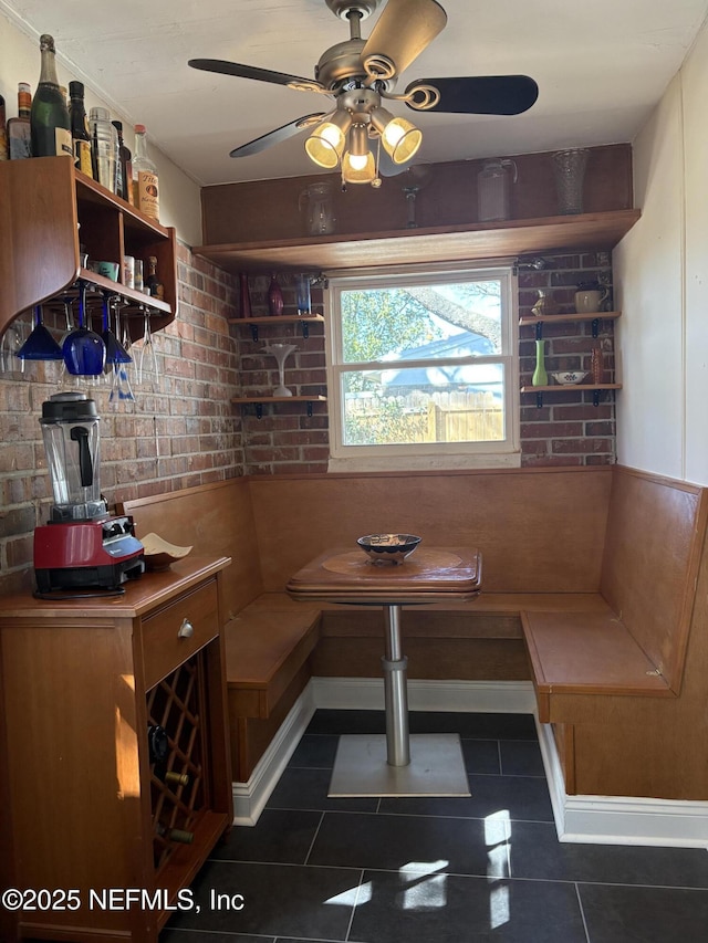 dining room featuring dark tile patterned flooring, brick wall, and breakfast area