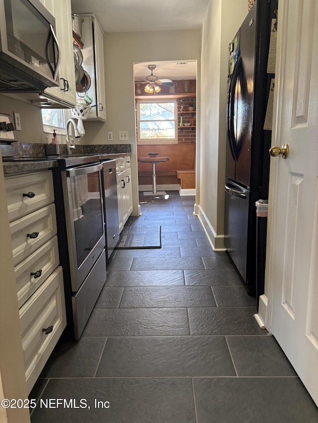 kitchen with dark countertops, white cabinets, baseboards, and appliances with stainless steel finishes