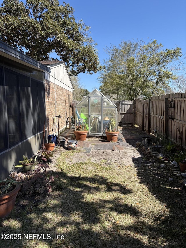 view of yard with a greenhouse, an outbuilding, and a fenced backyard