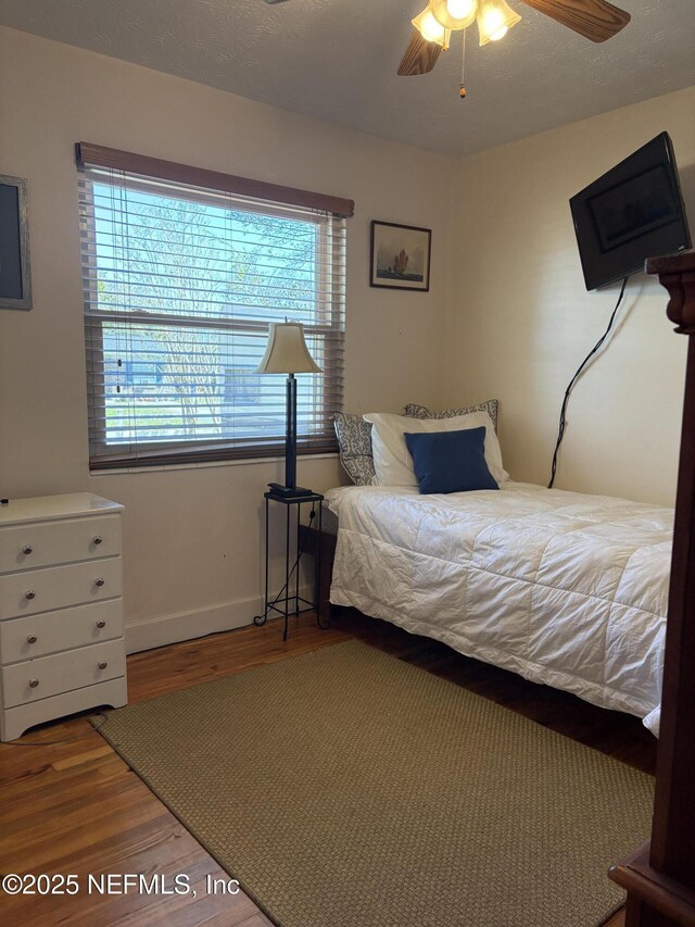 bedroom with a ceiling fan, wood finished floors, and baseboards