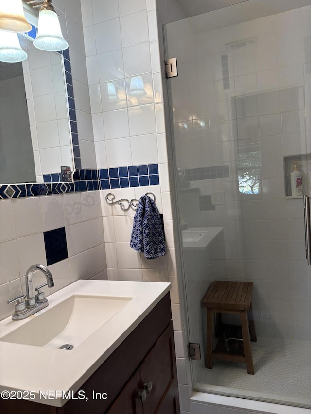 full bath featuring backsplash, a shower stall, tile walls, and vanity