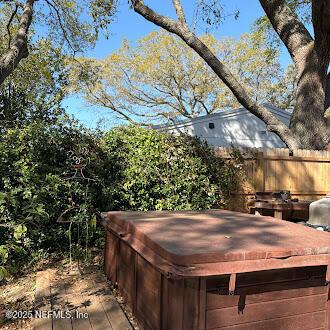 view of patio / terrace featuring a hot tub, a deck, and fence