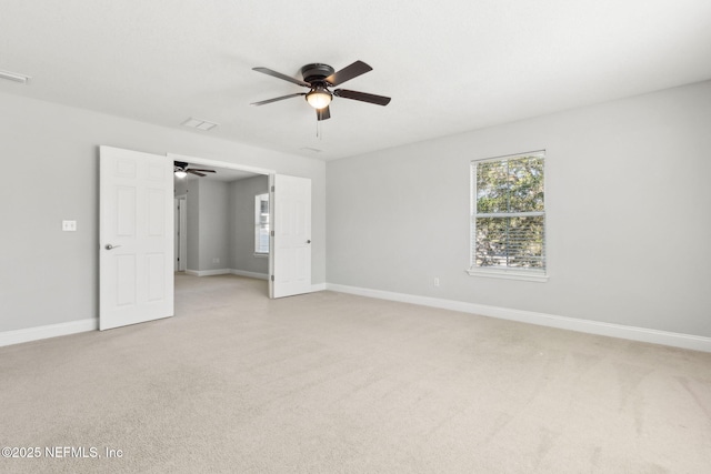 spare room featuring a ceiling fan, light colored carpet, and baseboards