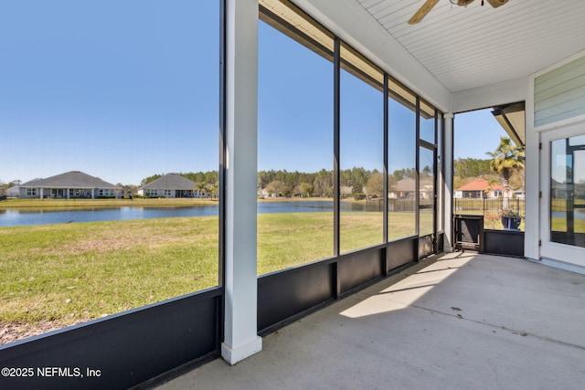 unfurnished sunroom with ceiling fan and a water view