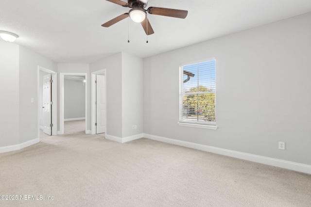 spare room with light colored carpet, baseboards, and ceiling fan