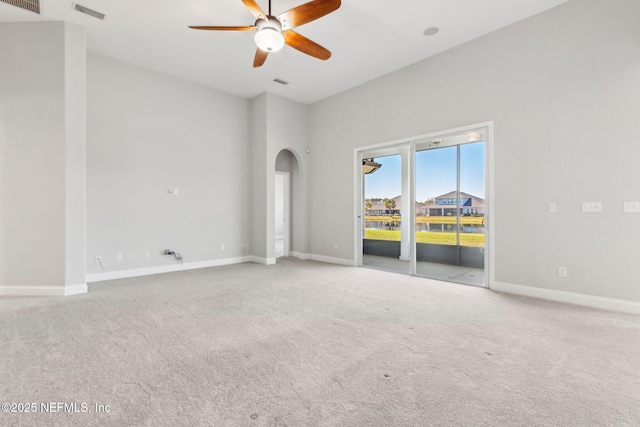 unfurnished room with carpet, arched walkways, visible vents, and baseboards