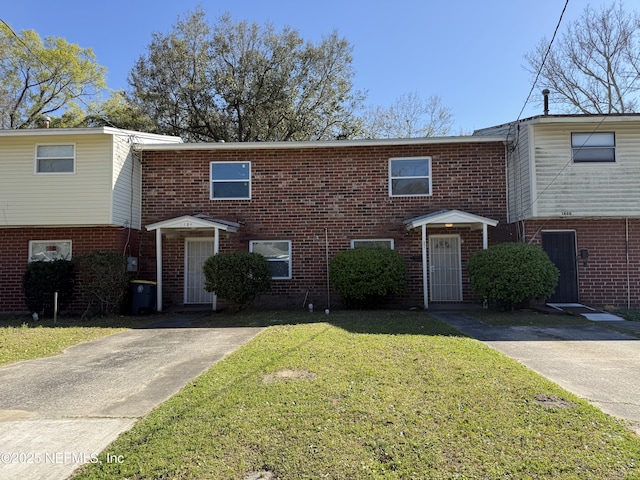 view of property with brick siding and a front lawn