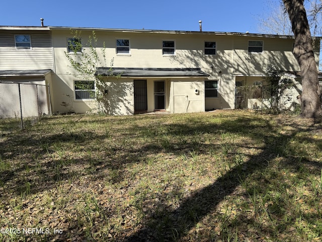 back of property with a yard and fence