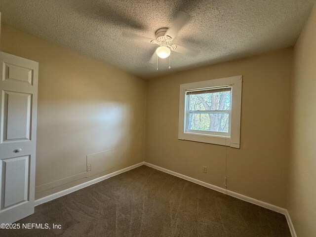 unfurnished room with a textured ceiling, dark colored carpet, and baseboards