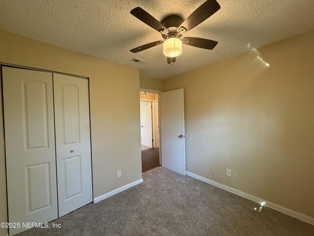 unfurnished bedroom featuring a closet, visible vents, carpet flooring, a textured ceiling, and baseboards