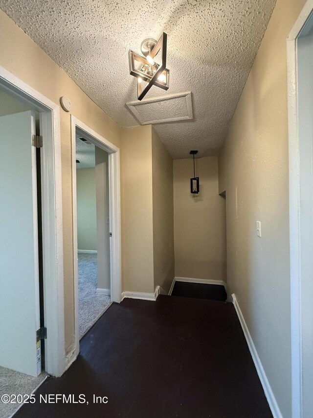 hallway with baseboards and a textured ceiling